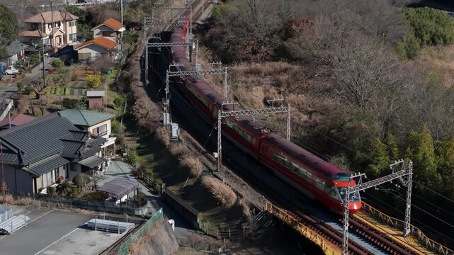 Drone footage of Odakyu Romancecar GSE train in forest landscape