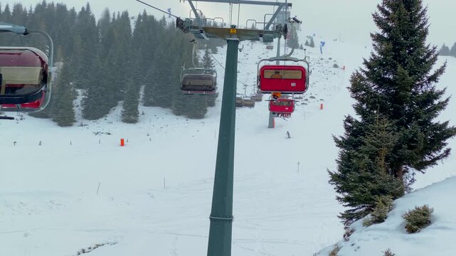 A wide-angle shot of skiers on a chairlift at Alpe di Siusi in the Dolomites. A panoramic shot of the lift ascending the snow-covered slopes of the Seiser Alm. Winter sports in the Italian Alps skiers