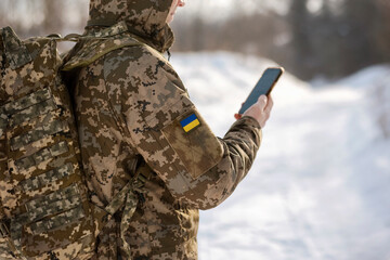 Naklejka premium Military Soldier with Backpack Using Phone in Winter. Military Navigation Tactical NAV Smart Digital in Ukrainian Soldier Hands.