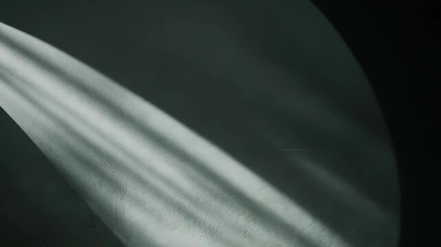 Abstract shadows and light rays are forming flowing curvilinear shapes and sharp parallel lines on a textured surface, creating a dynamic interplay of contrasting tones and minimalist design
