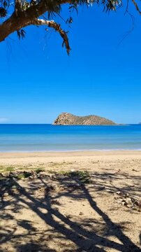 4K Vertical cinematic view of Souani beach in Al Hoceima, Morocco. Turquoise Mediterranean sea and mountains under a blue sky.