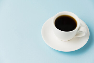 Obraz premium Espresso in a white cup on a blue paper background with copy space. Concept of morning planning for the day