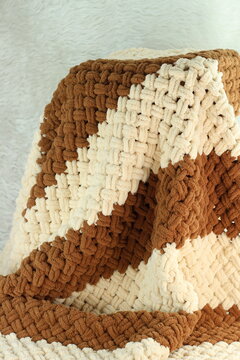 Handmade beige and brown puffy blanket with large loops on furry white blanket.