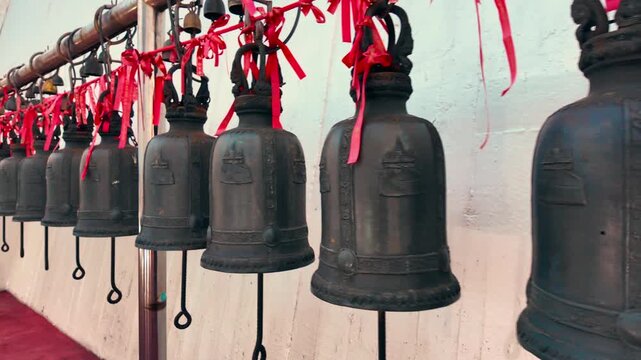 Bronze temple bells hanging in row in Wat Saket Buddhist temple, Ornate thai wind bells along railing 4k