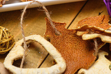 Handmade Christmas garland made of dried orange peels in star and tree shapes on a rustic wooden table.