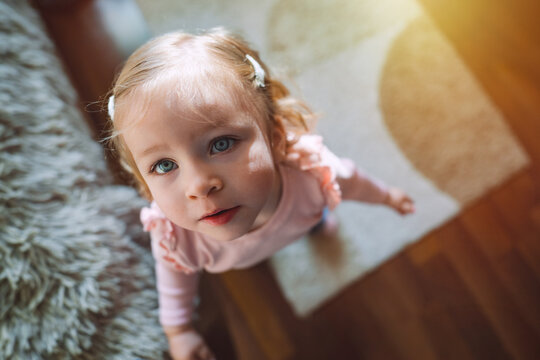 Little adorable cute infant girl at the age of 1.5 years is looking upwards. Childhood and family concept. High quality photo.