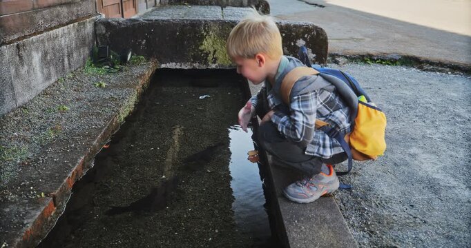 Adorable young boy feeding fish in old Japanese village - slow motion