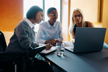 Diverse team working together around a laptop in a modern office