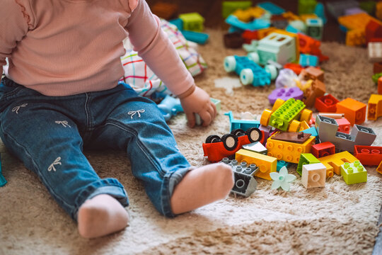 Girl in pink clothes is playing construction set for children on the floor. Childhood and education concept. High quality photo