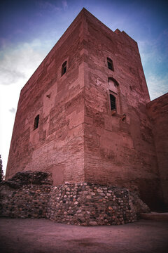 View of an ancient red stone tower reaching towards the sky, a silent witness to centuries of history in Granada, Andalusia, Spain.