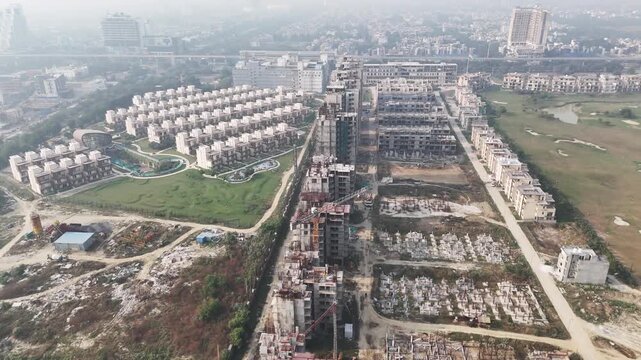 Aerial view of a developing residential township in Noida, showing under-construction high-rise apartments, plotted housing clusters, internal roads, and landscaped green zones.