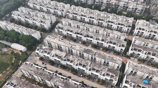 Drone footage capturing Noida&rsquo;s mixed landscape, with planned housing rows, open green fields, construction sites, and city infrastructure fading into visible air pollution haze.