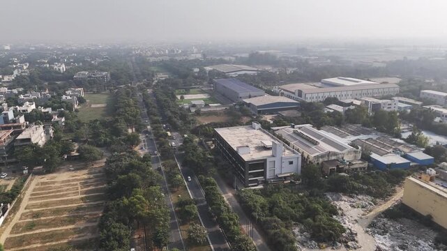 Top-down aerial of Sector 31 Alpha I, Greater Noida, capturing factories, logistics units, and landscaped avenues amid mild air pollution and morning haze.