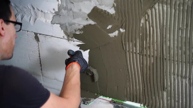 A builder lays tiles on a wall in a residential building