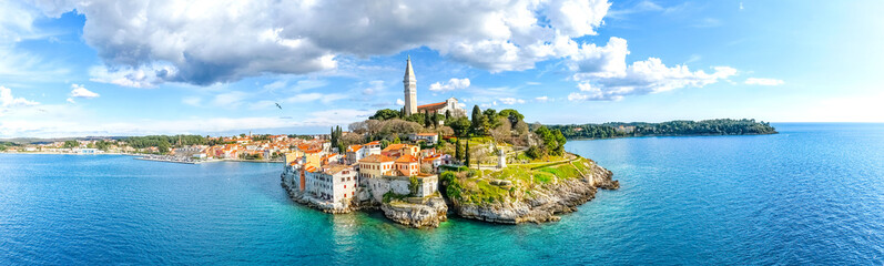Bright aerial view of Rovinj old town peninsula with historic church, rocky coast and clear turquoise Adriatic Sea