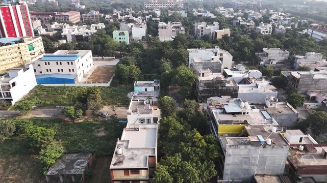 Drone video over Greater Noida with clustered homes, scattered greenery, and a large open ground at the center, highlighting planned urban living and open community spaces.