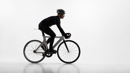 Obraz premium Professional cyclist riding road bike in studio isolated on white background. Concept of endurance training, competitive cycling, fitness lifestyle, sport performance, minimal clean design.