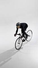 Obraz premium Road cyclist in aerodynamic position riding bicycle in studio. Concept of professional cycling, speed optimization, racing posture, performance training, competitive sport, minimal background.
