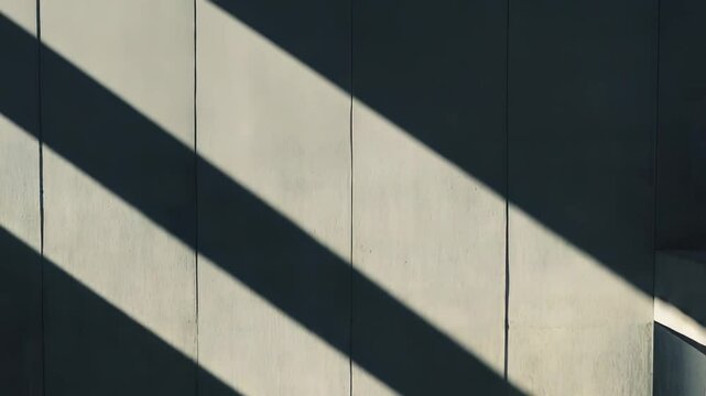 Minimalist architectural space featuring concrete walls and floor, creating geometric patterns and depth through strong contrasting natural light and dark shadows