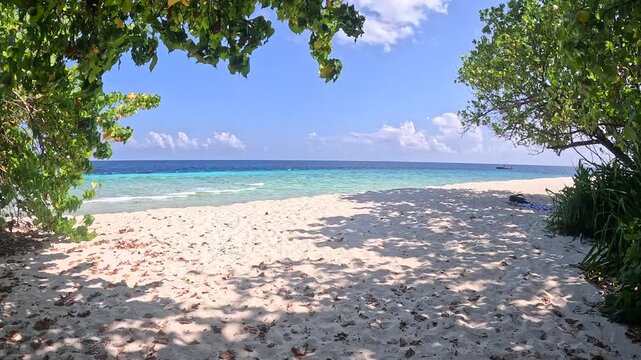 Person walking along white sand beach in Ukulhas Maldives with palm trees and turquoise water