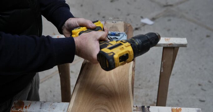 The Art of Crafting: A carpenter meticulously works on a wooden plank with a power drill, embodying skill and focus.