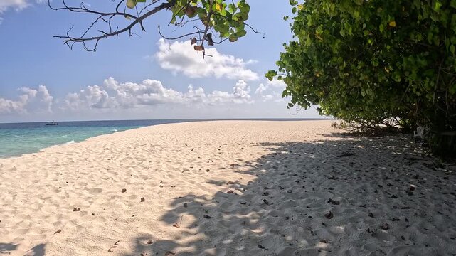 Person walking along white sand beach in Ukulhas Maldives with palm trees and turquoise water