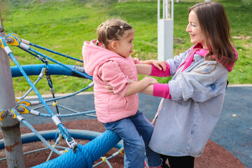 Obraz premium Happy Caucasian mother playing with little daughter at park playground