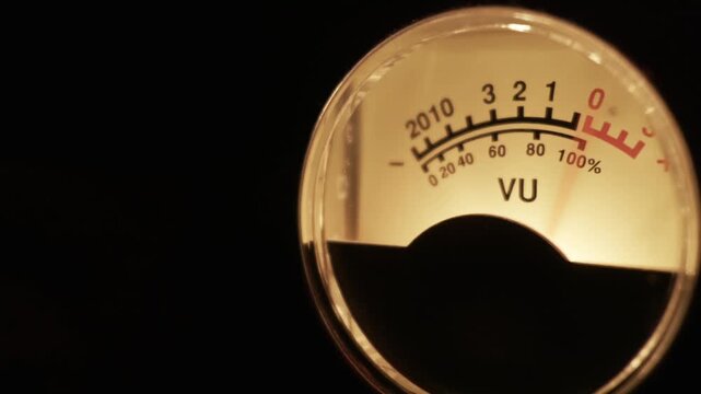 A close-up of a retro VU meter shows the needle measuring a sound signal, peaking in the red zone. Concept of audio engineering, music production, broadcasting, and vintage technology.