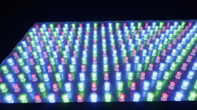 A close-up shot of an RGB LED panel with diodes flashing and changing colors. Concept of modern technology, digital displays, electronic components, and vibrant visual effects.