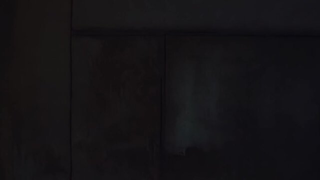 Warm sunlight illuminates an aged window frame, casting strong, defined light rays and shadows onto a textured, dark wall, symbolizing dawn and new beginnings in a quiet, contemplative atmosphere