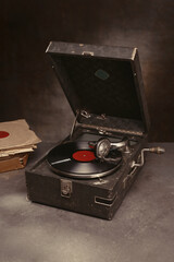 Portable gramophone with vinyl records. Gramophone with a handle for listening music. Selective focus.