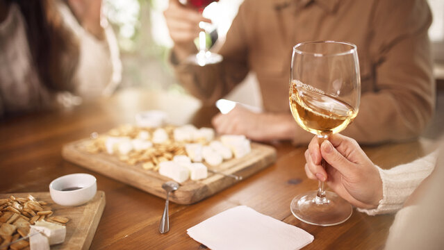 White wine glass with snacks during casual social dinner at home. Concept of lifestyle wine promotion, horeca marketing, social media advertising, everyday beverage consumption, hospitality visuals.