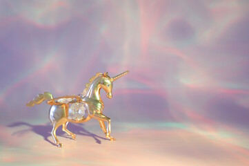 A unicorn figurine on a pink rainbow background.