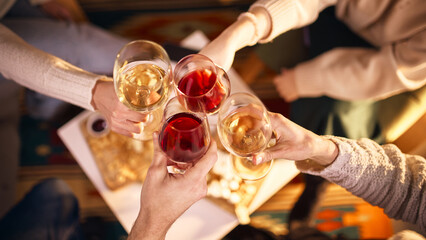 Friends clinking wine glasses during cozy evening gathering at home. Concept of social connection, celebration party, wine culture, relaxed lifestyle, beverage branding, leisure time.