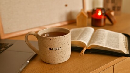 Cozy morning scene with a mug that says "Blessed" and an open Bible