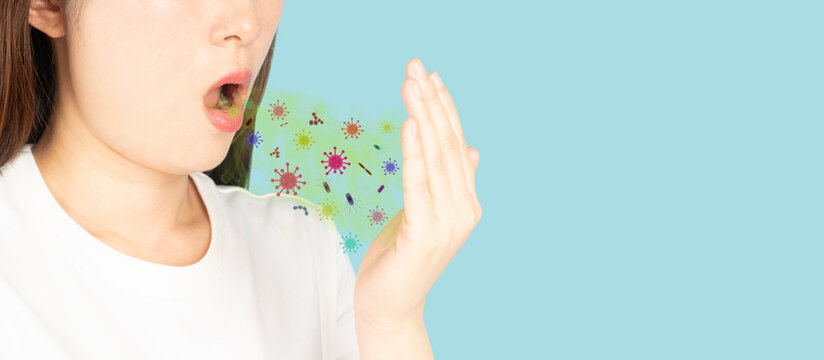 Woman checking her oral with bad breath on blue background. Smelly mouth with bacteria and virus. Causes of halitosis include poor oral hygiene, foods and drinks, and health conditions.