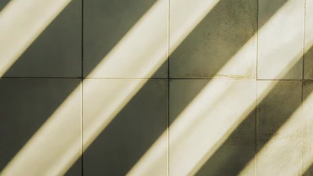 Sunlight casts bold diagonal stripes across textured ceramic tiles, creating a graphic play of light and shadow and a minimalist geometric pattern on a clean surface