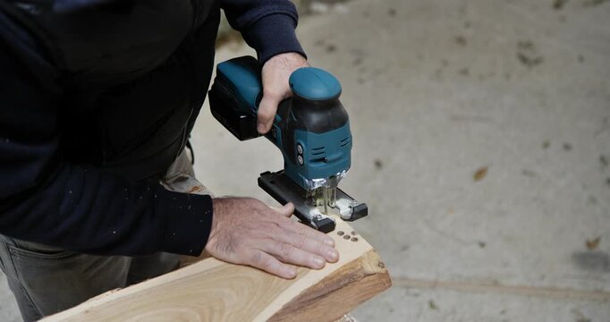 A skilled craftsman uses a hand saw to cut a wooden board in a carpentry workshop, utilizing professional equipment and tools for a home construction and repair project