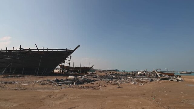 Construction of a wooden ship. Shipyard of traditional Dhow wooden boat on Iranian Qeshm Island. Tradition Lenj Fishing Boat in Qeshm Island in Southern Iran. Old wooden stealth smuggler's ship.