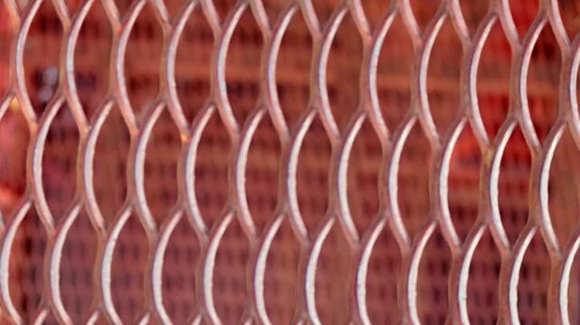 Close view shows metal mesh with repeating curved openings. Video includes refocus to distant plane where similar metal mesh appears.