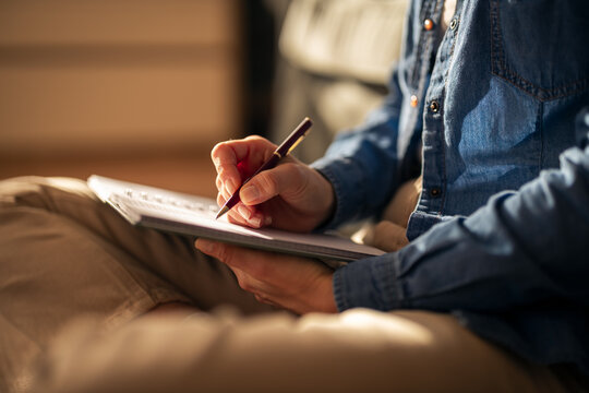 Person writing notes in diary at home