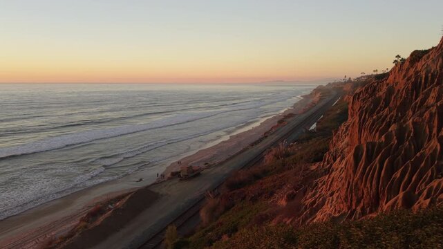 Sandstone Cliffs in Del Mar, California at sunset. People enjoy a walk on the beach. Slow zoom in shot.