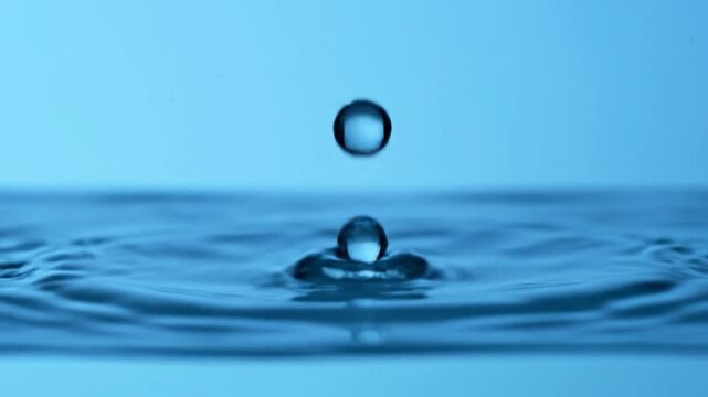 A single water drop creating a crown effect upon impact with the surface of water