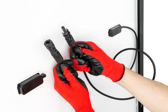 Gloved hands holding MC4 connectors for solar photovoltaic panels (plug and socket). Alternative and renewable energy concept. Isolated on white background. Cut out.