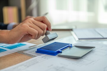 A person stamping a document with a rubber stamp.