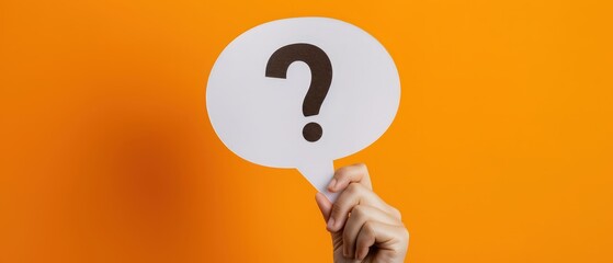 Hand holding white speech bubble with question mark on bright orange background, representing question, inquiry, help, communication, support, problem solving and information concept.