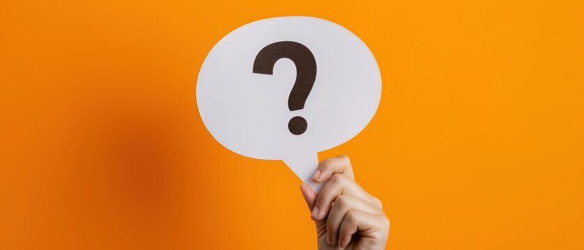 Hand holding white speech bubble with question mark on bright orange background, representing question, inquiry, help, communication, support, problem solving and information concept.