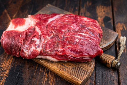 Raw beef brisket with cleaver on rustic wooden table, top view with copy space, fresh meat cut for barbecue and slow smoking