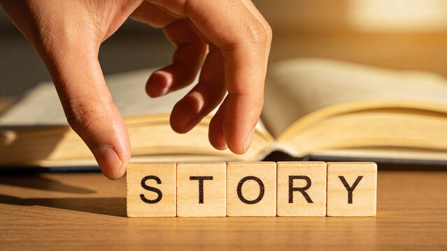 Hand Placing Wooden Blocks Spelling Story Near Open Book