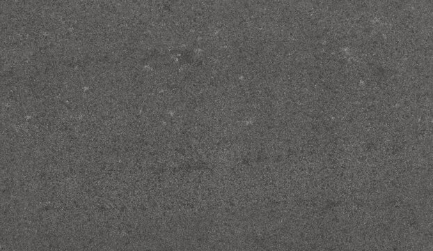 A uniform dark charcoal grey material close-up. It has a rough, slightly granular texture with scattered lighter specks, like weathered stone or industrial concrete